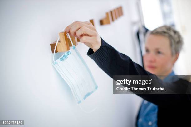 Berlin, Germany Symbolic image on the subject of the containment of the coronavirus, COVID-19, SARS-CoV-2. A woman takes a mouth guard from a coat...