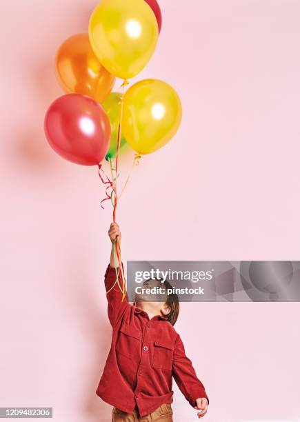 enfant mignon retenant des ballons colorés d’hélium sur le fond rose. il est heureux. - child balloon studio photos et images de collection