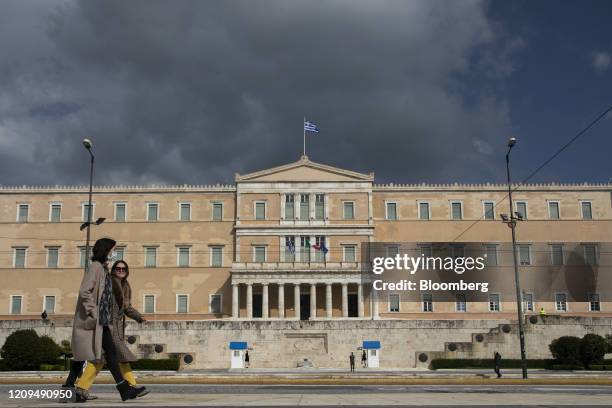 Women walk in Syntagma Square as the Greek parliament building stands beyond in Athens, Greece, on Tuesday, April 7, 2020. Europes fiscal stalemate...