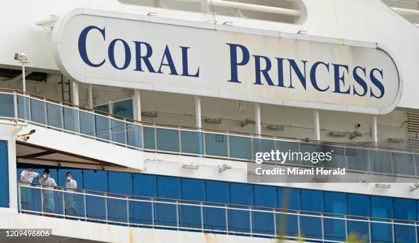 Los miembros de la tripulación del crucero Coral Princess miran desde su balcón hacia PortMiami el domingo 5 de abril de 2020 en Miami.