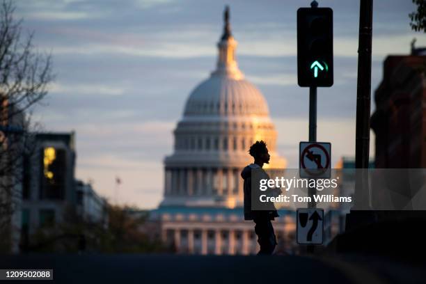 Man crosses North Capitol Street on M Street during the coronavirus outbreak on Friday, April 3, 2020.