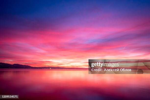 dark violet clouds with orange sun light and pink light in wonderful twilight sky on lake bodensee in lindau - purple sky fotografías e imágenes de stock