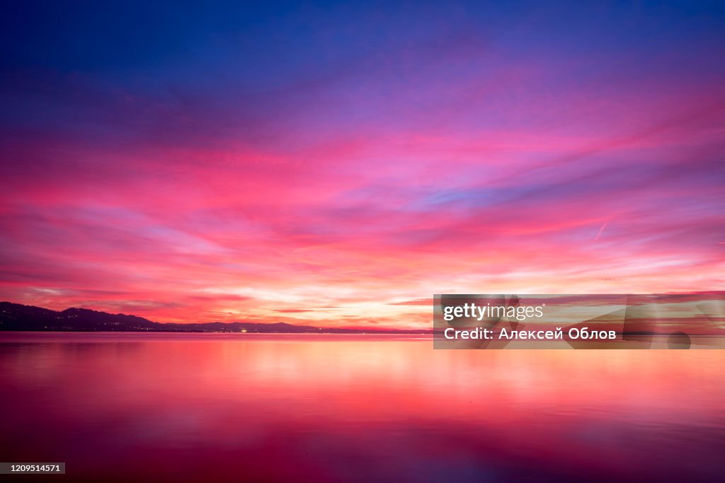 Dark violet clouds with orange sun light and pink light in wonderful twilight sky on lake Bodensee in Lindau