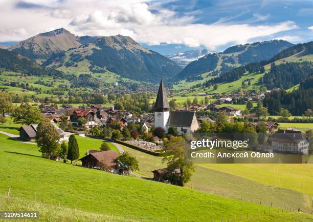 landscape near gstaad, summer view to saanen church and village - gstaad stockfoto's en -beelden