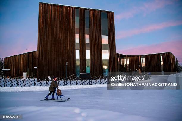 Woman slides on the snow in front of the building of the Sami Parliament of Finland in Inari, Finland, on December 6, 2019. - Until the middle of the...