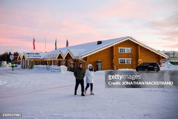 Couple of passers-by walk on the snow in Inari, Finland on December 6, 2019. - Until the middle of the last century, the 10 languages of the...