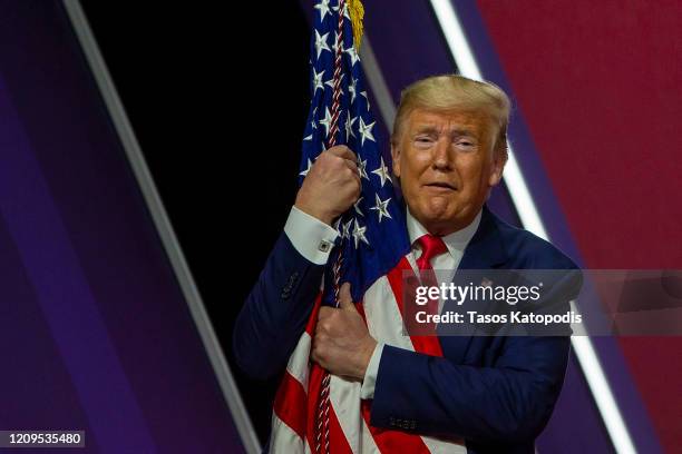 President Donald Trump hugs the flag at the annual Conservative Political Action Conference at Gaylord National Resort & Convention Center February...