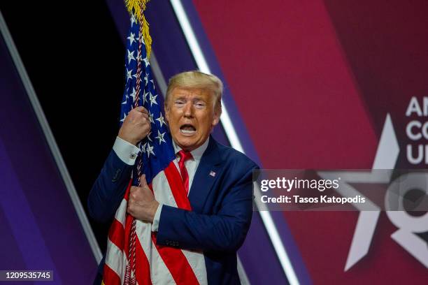 President Donald Trump hugs the flag of the United States of America at the annual Conservative Political Action Conference at Gaylord National...