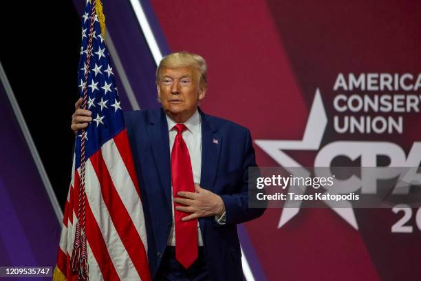 President Donald Trump hugs the flag of the United States of America at the annual Conservative Political Action Conference at Gaylord National...