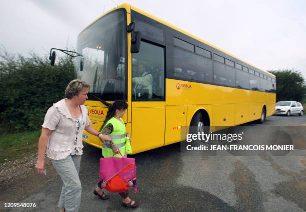 Une maman tient par la main sa fille affublée d'un gilet fluorescent le 02 septembre 2008 devant un car de ramassage scolaire jaune à...