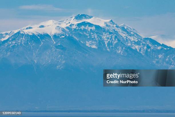 Snow-covered Mount Olympus as seen from Thessaloniki city in Greece after the rare weather and the April snowfall, the mountain is behind the sea,...