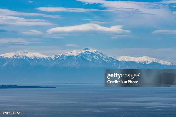 Snow-covered Mount Olympus as seen from Thessaloniki city in Greece after the rare weather and the April snowfall, the mountain is behind the sea,...