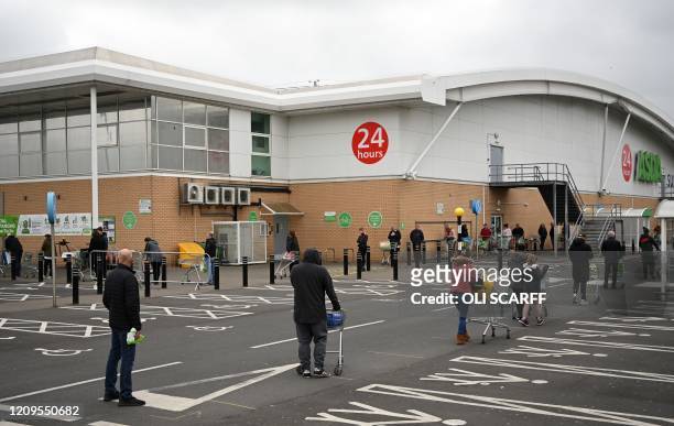 Shoppers queue using social distancing outside an Asda supermarket in Gateshead, north-east England on April 9, 2020 as Britain continued to battle...