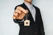 concept of selling real estate. Renting an apartment. Rent a room. Holding out house keys on a house shaped keychain