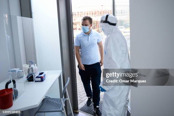 Health worker wears a protective mask and suit as she opens the door to a patient before performing an antibody test for COVID-19 at the Dworska...