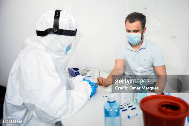 Health worker wears a protective mask and suit as she extracts blood from a patient to perform an antibody test for COVID-19 at the Dworska Hospital...