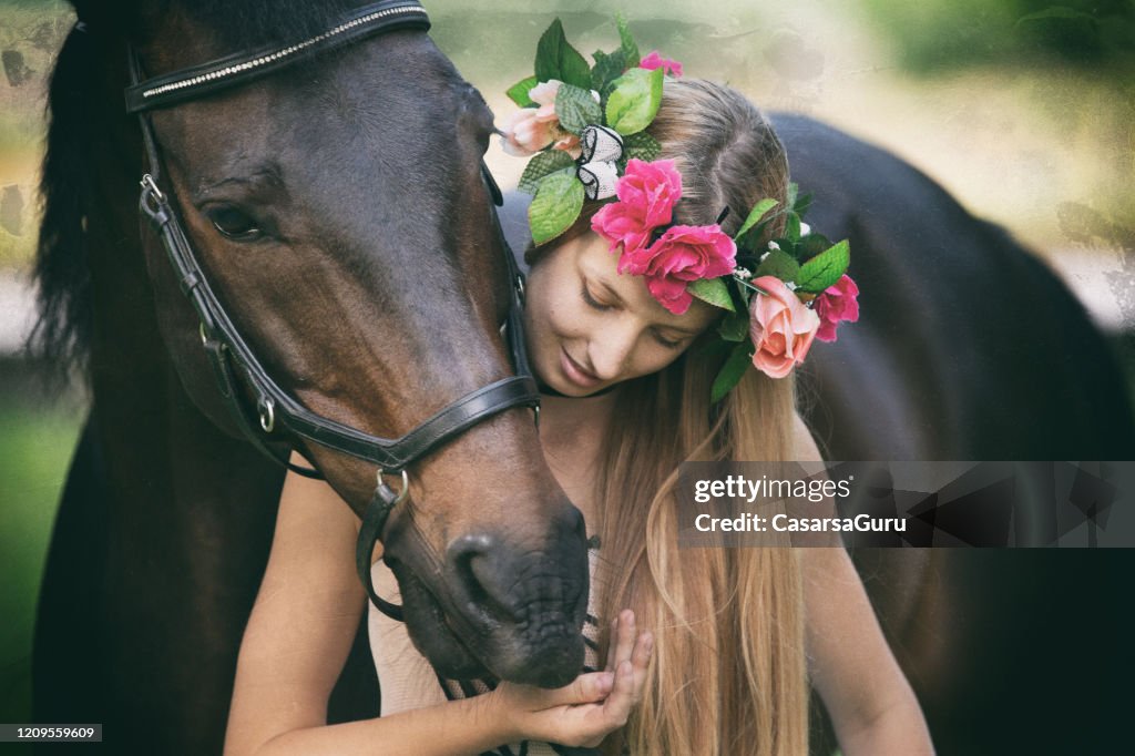 Pferd Umarmung lächelnde junge Frau in Blumenkrone - Stockfoto