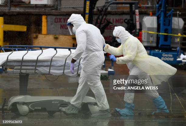 Medical personnel move a deceased patient to a refrigerated truck serving as make shift morgues at Brooklyn Hospital Center on April 09, 2020 in New...