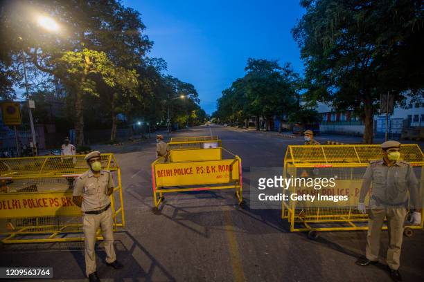 Indian policemen stand guard in front the sealed Bengali Market after three people were found infected with coronavirus in the area, as India remains...