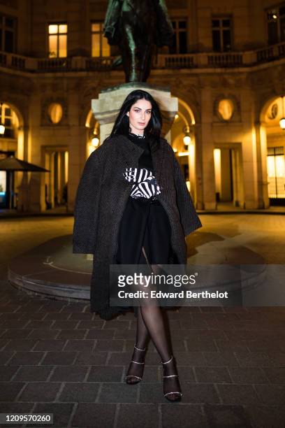 Fiona Zanetti wears a long coat, a black dress, black and white striped gloves, outside the MyTheresa x Amina Muaddi dinner at Froufrou Place Edouard...