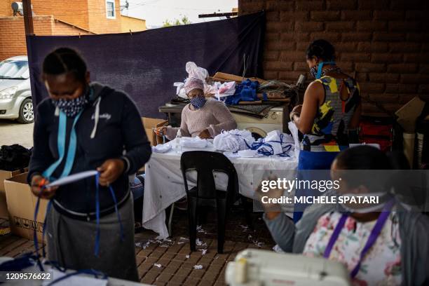 Women cut and sew cotton fabrics into pieces used to manufacture reusable face masks in Johannesburg's Alexandra township, on April 8, 2020....