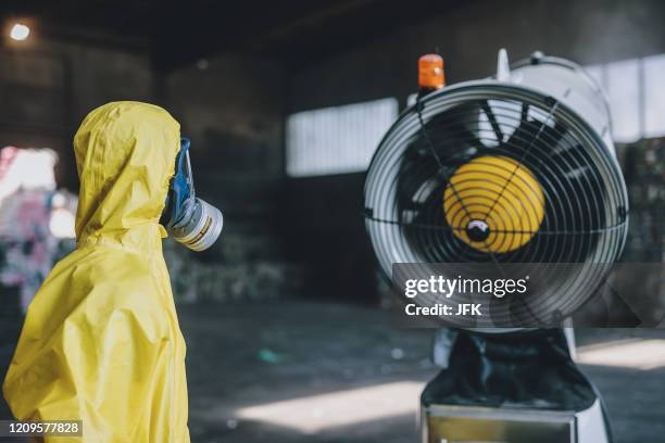 An employee wearing protective equipment stands next to a snow cannon during a press conference on "Unique innovation - disinfecting with snow...