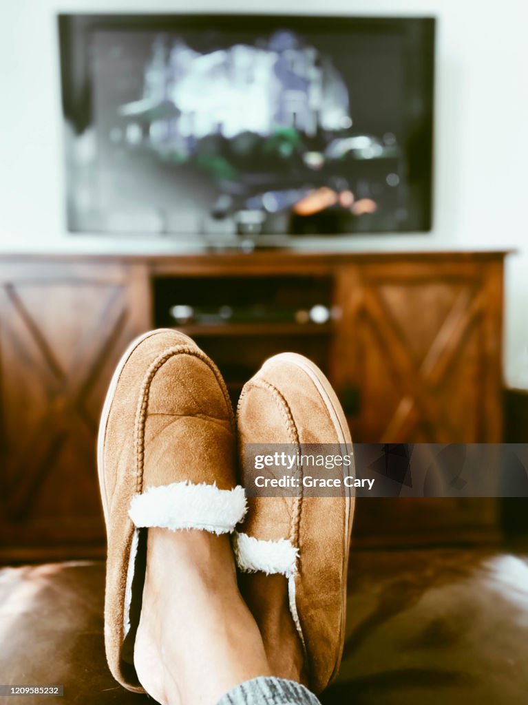 Woman's Slippered Feet on Ottoman in Front of TV