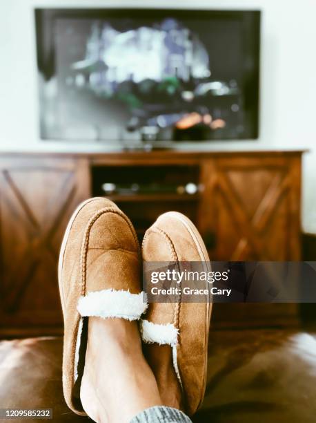 woman's slippered feet on ottoman in front of tv - chinelo imagens e fotografias de stock