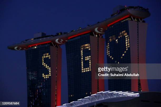 An illuminated "SG Love" on the facade of Marina Bay Sands and flag projections on the underbelly of the Sands SkyPark is seen on April 10, 2020 in...