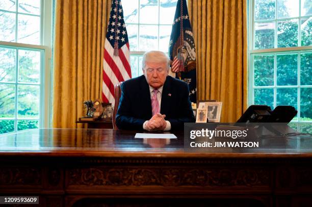 President Donald Trump prays at his desk as he participates in an Easter Blessing with Bishop Harry Jackson at the White House in Washington, DC, on...
