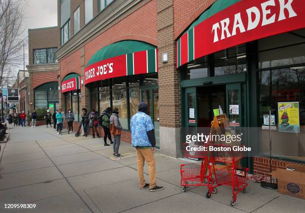 Customers line up outside the Trader Joe's grocery store in Coolidge Corner in Brookline, MA on April 8, 2020. The supermarket limits the number of...