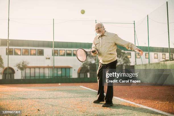 senior man playing tennis in a cloudy day - amateur tennis man stock pictures, royalty-free photos & images