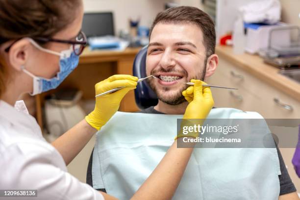 l'uomo alle parentesi graffe del dentista controlla - apparecchio ortodontico foto e immagini stock