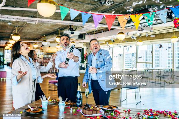 ontspannen stafmedewerkers die verjaardag met partijpopper vieren - party popper stockfoto's en -beelden