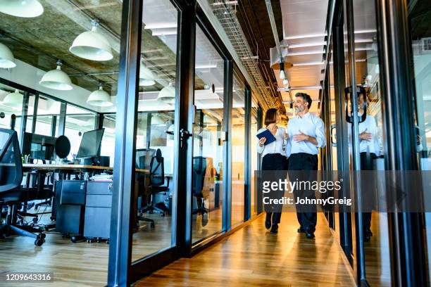 connected business associates walking down hallway - man talking to camera stock pictures, royalty-free photos & images