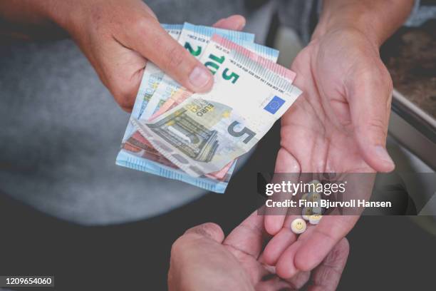 close up of hand with money buying party pills with smily face from dealer - trafficking stockfoto's en -beelden