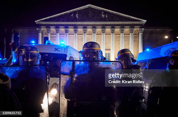 French Riot Policeman holds back a crowd gathered outside the French National Assembly to protest against French Prime Minister Edouard Philippe's...