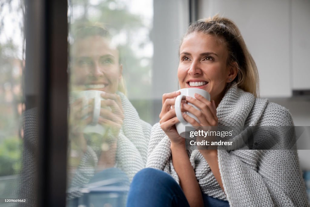 Mulher pensativa bebendo uma xícara de café em casa