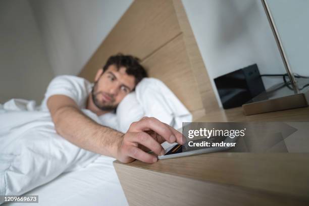 man waking up in the morning and snoozing the alarm - alarm clock on nightstand stock pictures, royalty-free photos & images