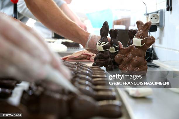 Chocolate maker finishes easter chocolate rabbits with a face mask on April 11, 2020 in Troyes amid the spread of the COVID-19 disease caused by the...