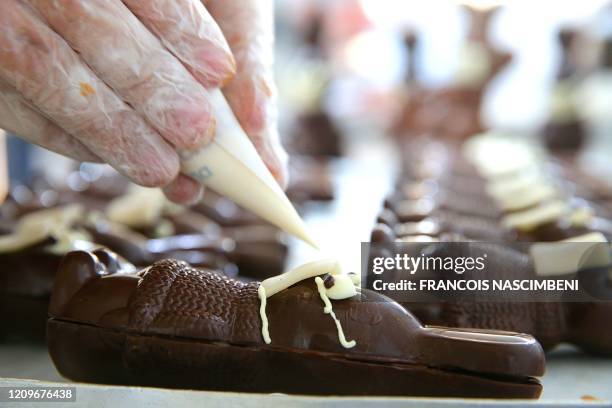 Chocolate maker finishes easter chocolate rabbits with a face mask on April 11, 2020 in Troyes amid the spread of the COVID-19 disease caused by the...