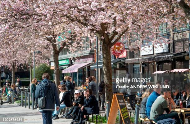 People sit at a cafe terrasse in central Stockholm, Sweden, on April 11, 2020 amid the new coronavirus COVID-19 pandemic. - Sweden has not imposed...