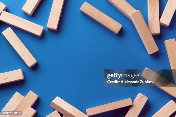 a pile of scattered wooden blocks on a blue background. construction game. destroy tower. copy space for text. - block removal game stock pictures, royalty-free photos & images