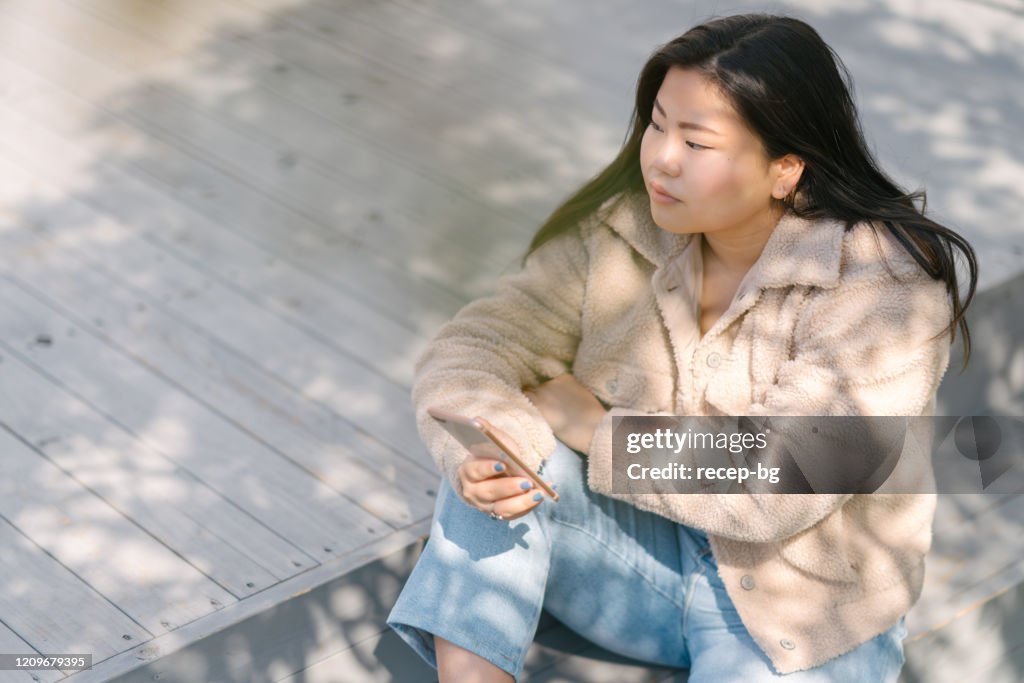 Young woman resting while using smart phone