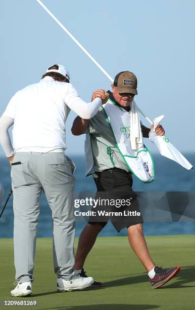 Sami Valimaki of Finland celebrates with caddie Kyle Roadley on the 18th green during the final round of the Oman Open at Al Mouj Golf Complex on...