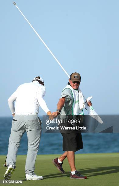 Sami Valimaki of Finland celebrates with caddie Kyle Roadley on the 18th green during the final round of the Oman Open at Al Mouj Golf Complex on...
