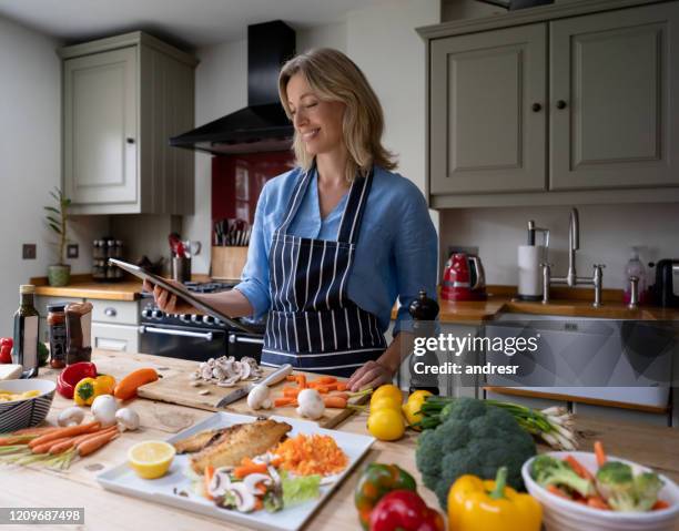 woman cooking at home following an online recipe - following recipe stock pictures, royalty-free photos & images