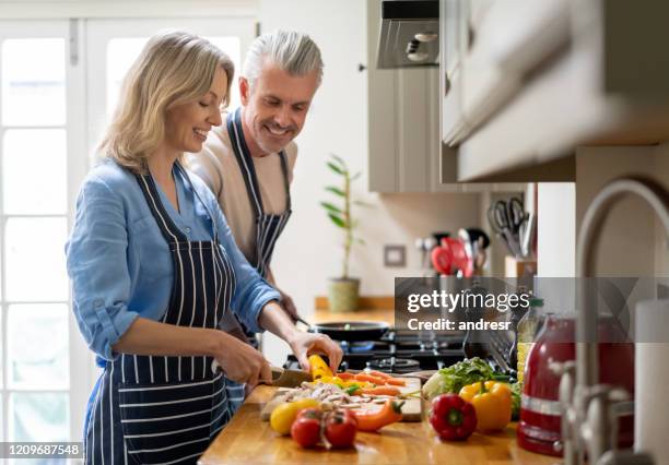 愛するカップルは、自宅で一緒に料理し、幸せを見て - middle aged couple cooking ストックフォトと画像