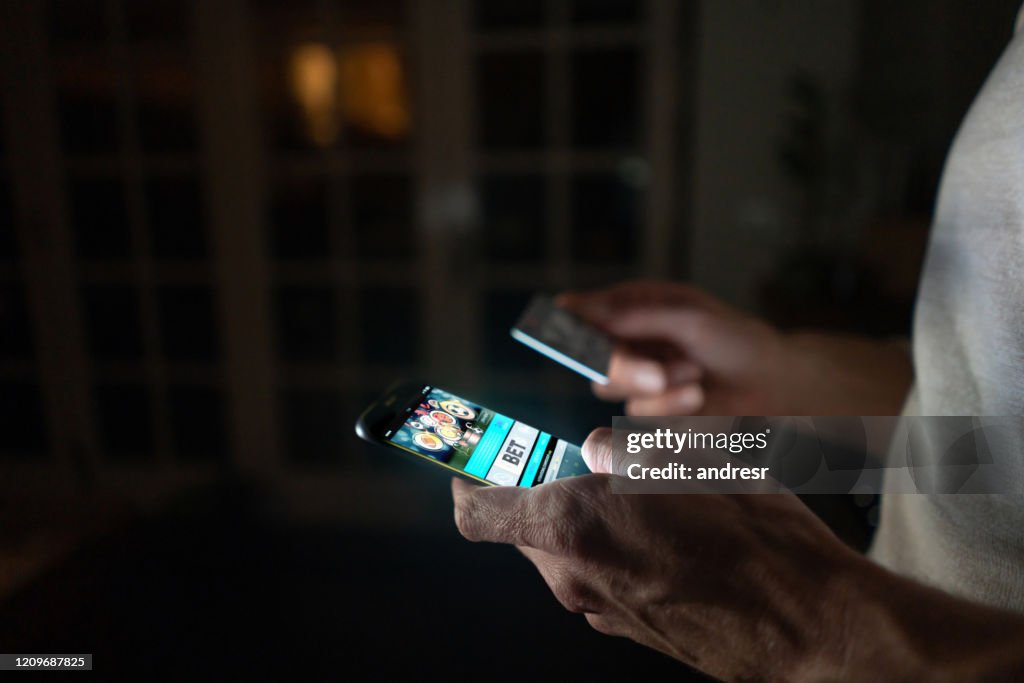 Hombre apostando en línea en casa en su teléfono celular