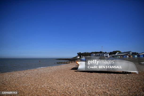 An upturned boat is pictured on the empty beach at Whitstable, south east England on April 11 as life in Britain continues over the Easter break,...